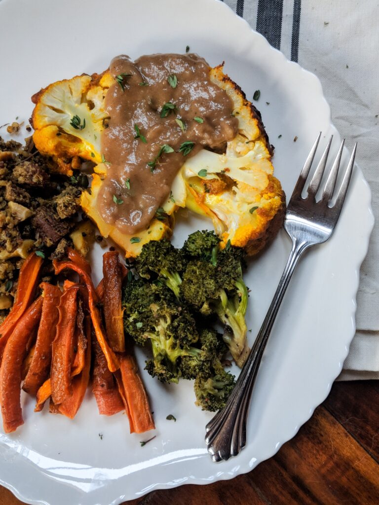 overhead image of a plate with roasted cauliflower, stuffed acorn squash, vegetables, and a fork