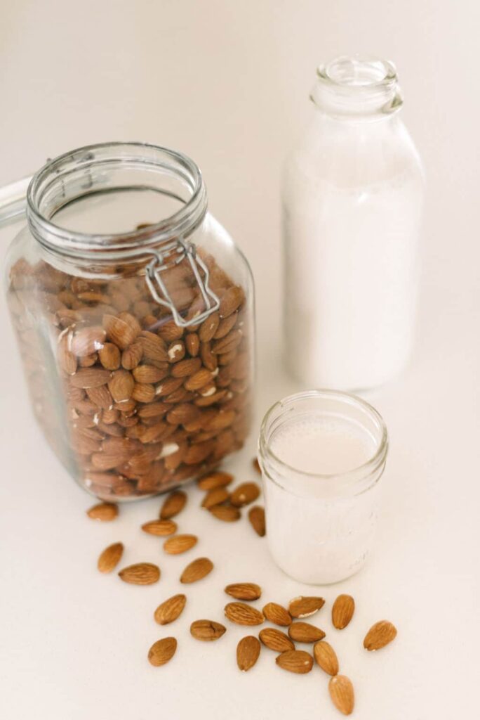 a jar of almonds next to a glass of almond milk depicting what to do with almond pulp