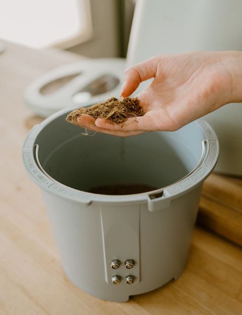 Woman's hand holding compost from her Lomi in her Lomi compost review