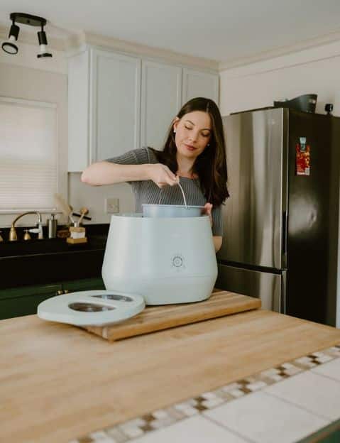 A woman using her Lomi compost machine in her kitchen.